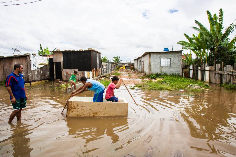 Crianças usam geladeira quebrada como barco para atravessar a rua no Jardim Pantanal Crianças usam geladeira quebrada como barco para atravessar a rua no Jardim Pantanal