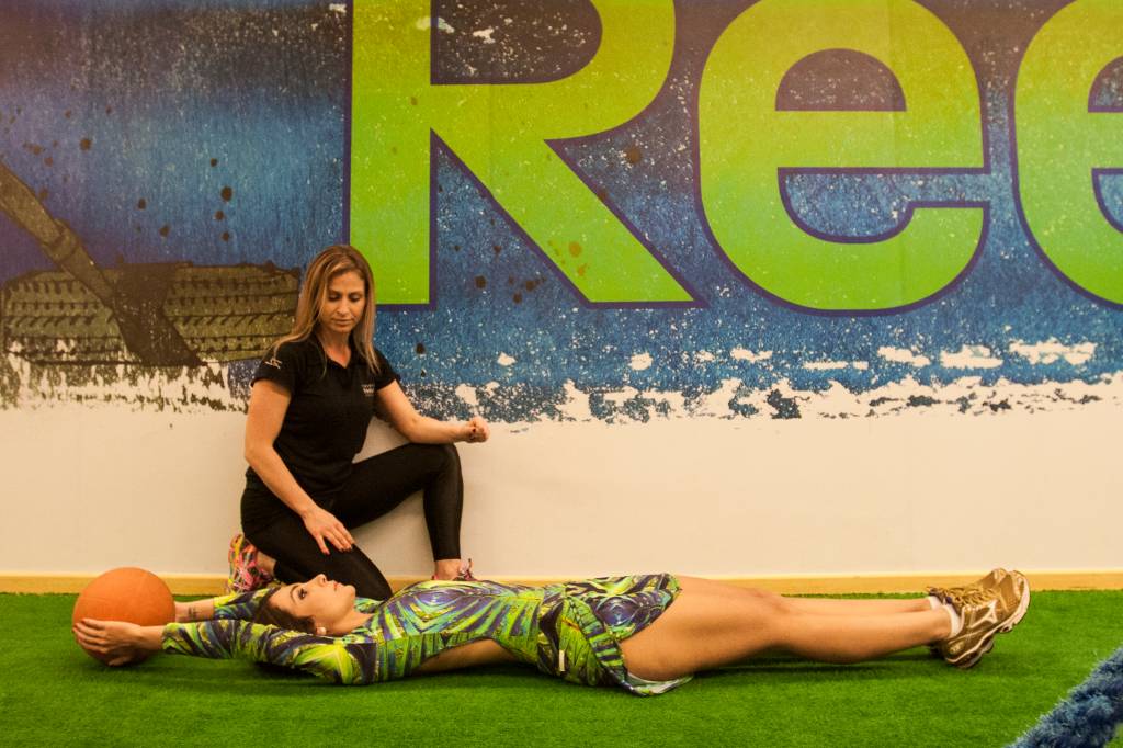 Abdominal com bola: usando um peso, eleve os bra&ccedil;os para tr&aacute;s e deixe as pernas esticadas. Quatro s&eacute;ries de vinte repeti&ccedil;&otilde;es.