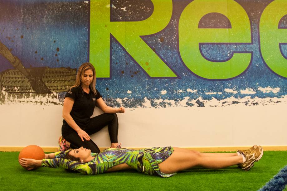 Abdominal com bola: usando um peso, eleve os bra&ccedil;os para tr&aacute;s e deixe as pernas esticadas. Quatro s&eacute;ries de vinte repeti&ccedil;&otilde;es.