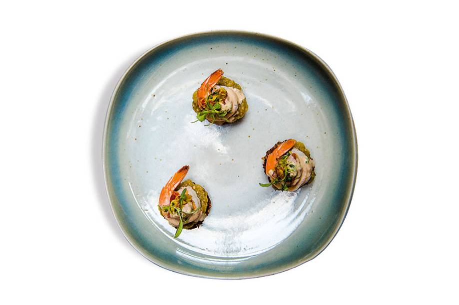 Acarajé de grão-de-bico: bolinho frito para ser coberta por patê de berinjela, camarão no vapor e brotos de coentro Acarajé de grão-de-bico: bolinho frito para ser coberta por patê de berinjela, camarão no vapor e brotos de coentro