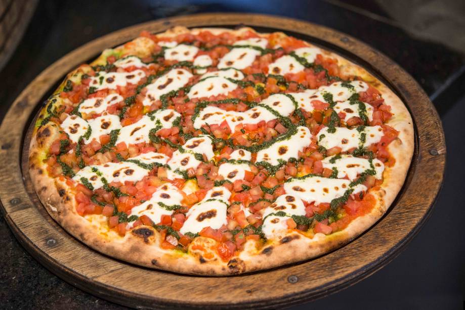 A cobertura de queijo burrata é complementada por cubinhos de tomate e molho pesto A cobertura de queijo burrata é complementada por cubinhos de tomate e molho pesto