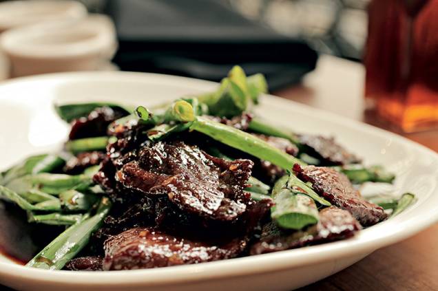 Mongolian beef traz fatias de carne na chapa carameladas no molho de shoyu e alho com cebolinha verde Mongolian beef traz fatias de carne na chapa carameladas no molho de shoyu e alho com cebolinha verde
