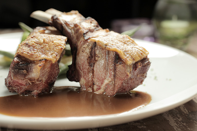 O par de costeleta de cordeiro vem coberto por molho de mostarda em grãos O par de costeleta de cordeiro vem coberto por molho de mostarda em grãos