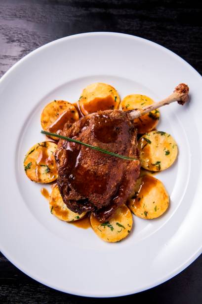 O confit de pato vem com a coxa e sobrecoxa sobre rodelas de batata sautée O confit de pato vem com a coxa e sobrecoxa sobre rodelas de batata sautée