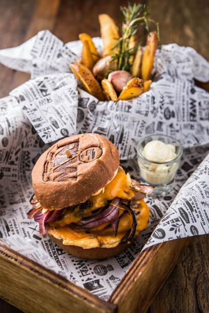 Dois discos de carne, queijo cheddar e cebola-roxa no pão australiano Dois discos de carne, queijo cheddar e cebola-roxa no pão australiano