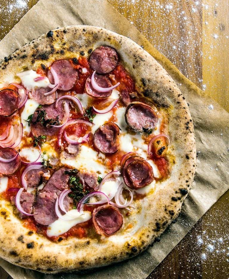 A pizza de calabresa, cebola-roxa, mussarela e orégano fresco A pizza de calabresa, cebola-roxa, mussarela e orégano fresco