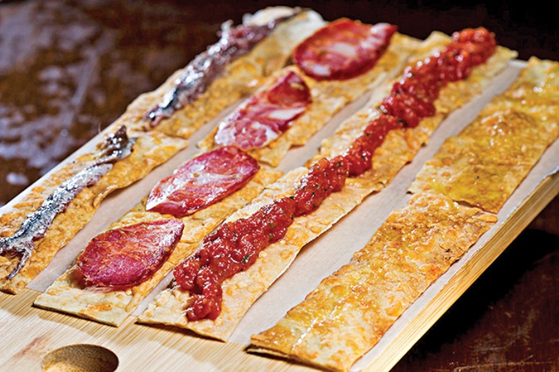 Terra, amore e fantasia: um quarteto de crostini fino com aliche, calabresa seca, tartare de tomate e azeite da Puglia