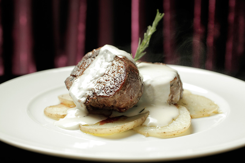 Sobre lâminas de batata, o filé-mignon é regado por molho de queijo gruyère Sobre lâminas de batata, o filé-mignon é regado por molho de queijo gruyère