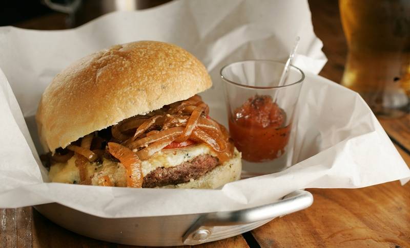 O hambúrguer é coberto de mussarela, creme de gorgonzola e cebola caramelada O hambúrguer é coberto de mussarela, creme de gorgonzola e cebola caramelada