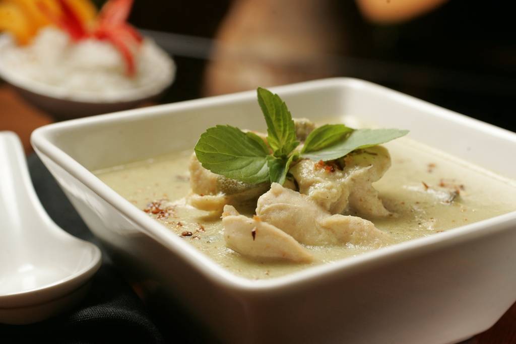 Curry verde de frango na companhia de arroz coberto por fatias de manga fresca Curry verde de frango na companhia de arroz coberto por fatias de manga fresca