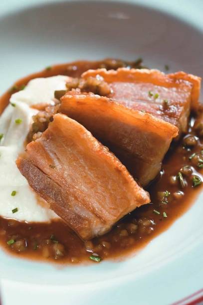 Entrada do francês Ici Bistrô: barriga de porco em fatias sobre purê de couve-flor Entrada do francês Ici Bistrô: barriga de porco em fatias sobre purê de couve-flor