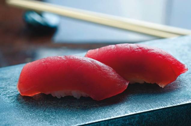 No japonês Jun Sakamoto: bolinhos de arroz cobertos por fatias de atum No japonês Jun Sakamoto: bolinhos de arroz cobertos por fatias de atum