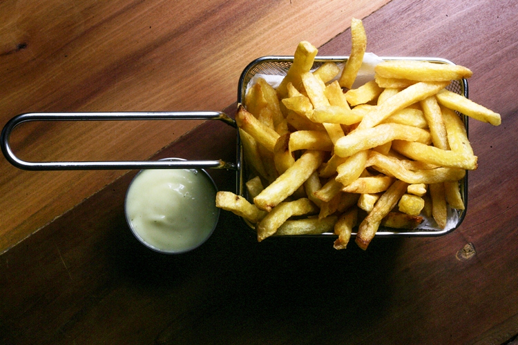 Porção de batata frita servida numa cestinha metálica Porção de batata frita servida numa cestinha metálica