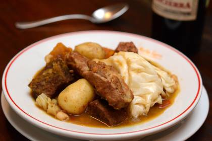 Prato fundo branco com cozido com carne, batata e repolho.