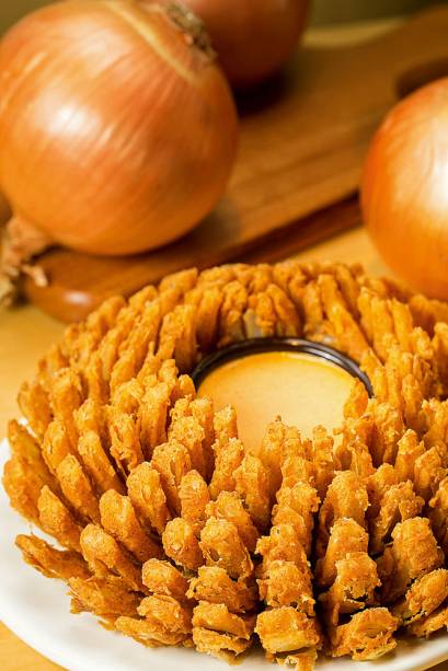 bloomin’ onion: cebola cortada em pétalas, empanada e frita bloomin’ onion: cebola cortada em pétalas, empanada e frita