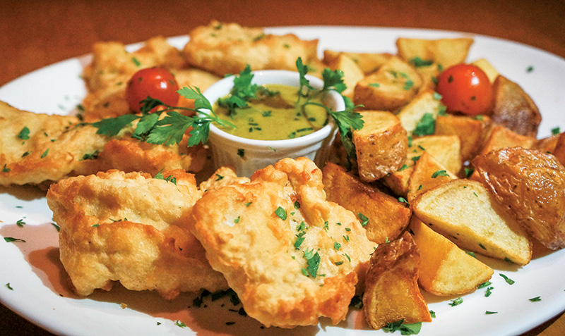 Merluza à milanesa acompanhada de batatas assadas e molho de alcaparras