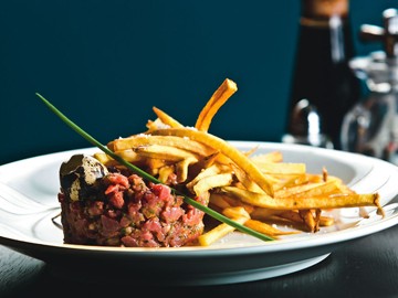 Ramona: steak tartare rico em condimentos na companhia de fritas Ramona: steak tartare rico em condimentos na companhia de fritas