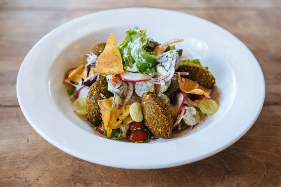 Faláfel: servido sobre salada de folhas, rabanete, pepino, cebola-roxa, uva e torrada ao molho de iogurte