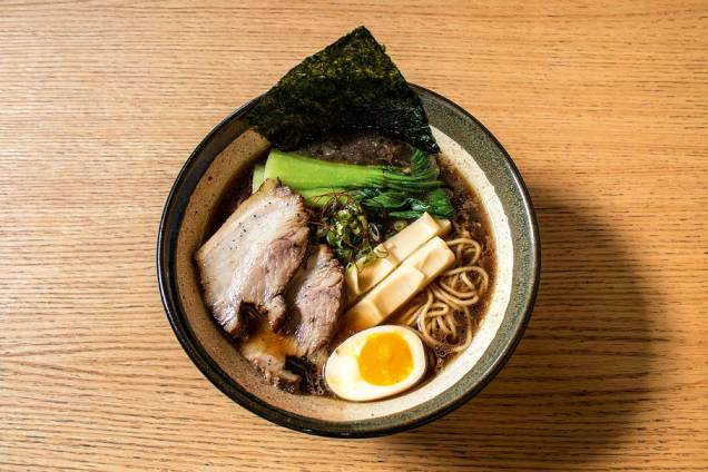 O shoyu lámen vem no caldo no estilo ton tori chintan, feito com porco e galinha, e seus toppings incluem barriga de porco, ovo e broto de bambu O shoyu lámen vem no caldo no estilo ton tori chintan, feito com porco e galinha, e seus toppings incluem barriga de porco, ovo e broto de bambu