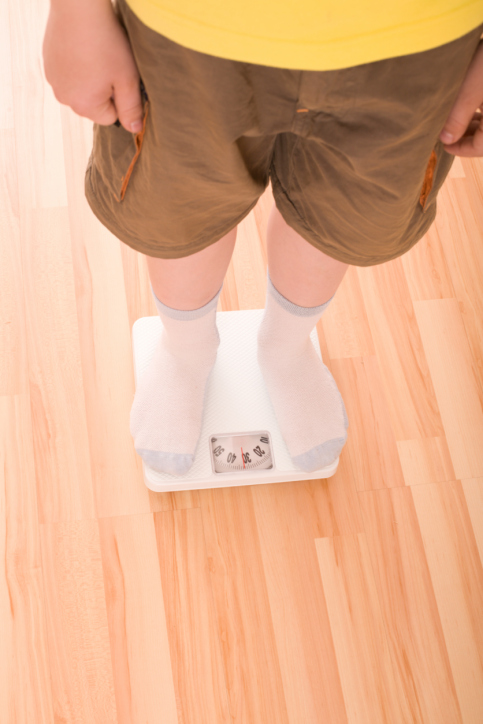 Boy measures weight on floor scales Boy measures weight on floor scales