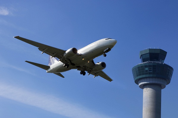 Olhando de baixo para cima, um avião em um céu azul, dando para ver sua parte inferior