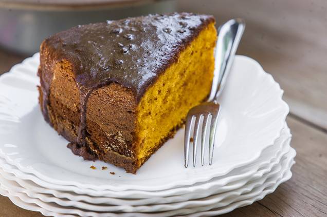 O bolo de cenoura é servido em fatia alta com cobertura de chocolate O bolo de cenoura é servido em fatia alta com cobertura de chocolate