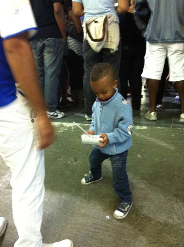 Pequeno integrante da bateria faz de latinha de refrigerante o seu tamborim Pequeno integrante da bateria faz de latinha de refrigerante o seu tamborim