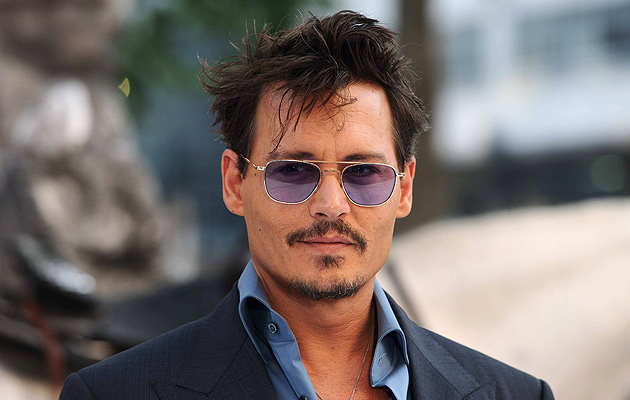 Foto deJohnny Depp usando óculos escuro e sorrindo levemente.