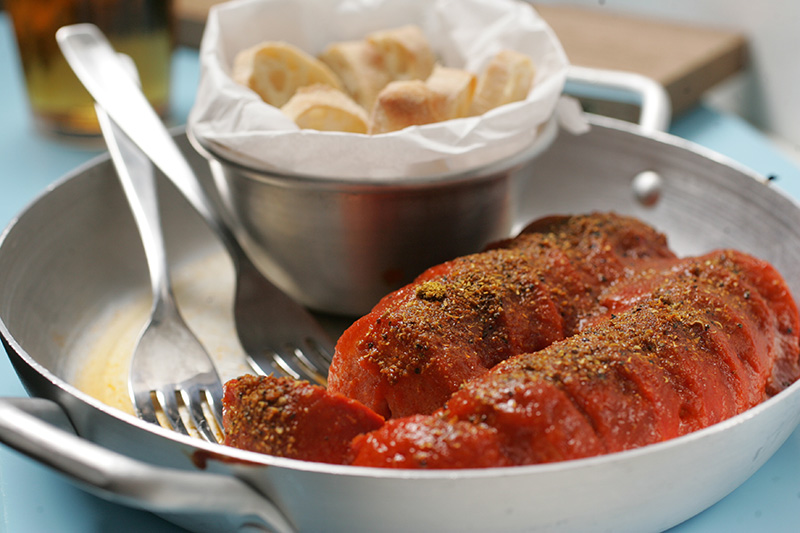 Currywurst: salsichões fatiados cobertos por um equilibrado molho de curry Currywurst: salsichões fatiados cobertos por um equilibrado molho de curry