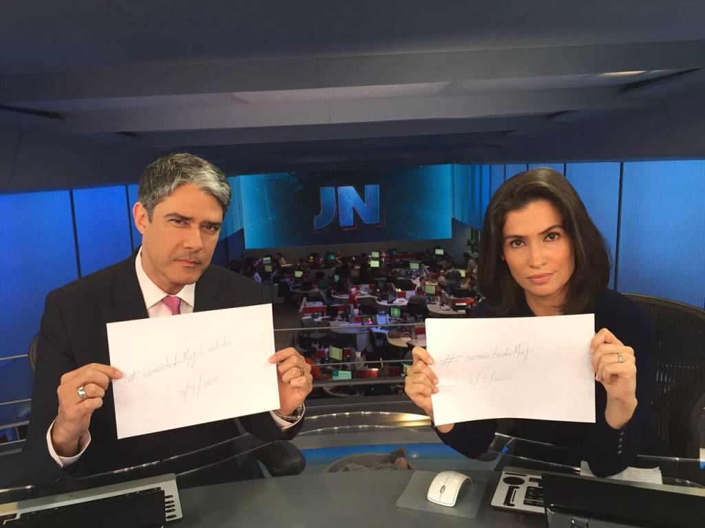 Os apresentadores do Jornal Nacional com o cartaz "Somos Todos Maju"