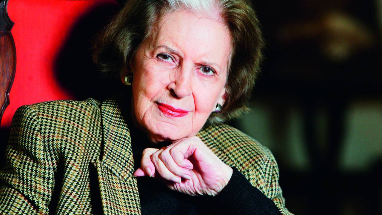 Retrato da escritora Lygia Fagundes Telles, ela está com paletó xadrez, blusa preta por baixo, tem os cabelos com corte chanel