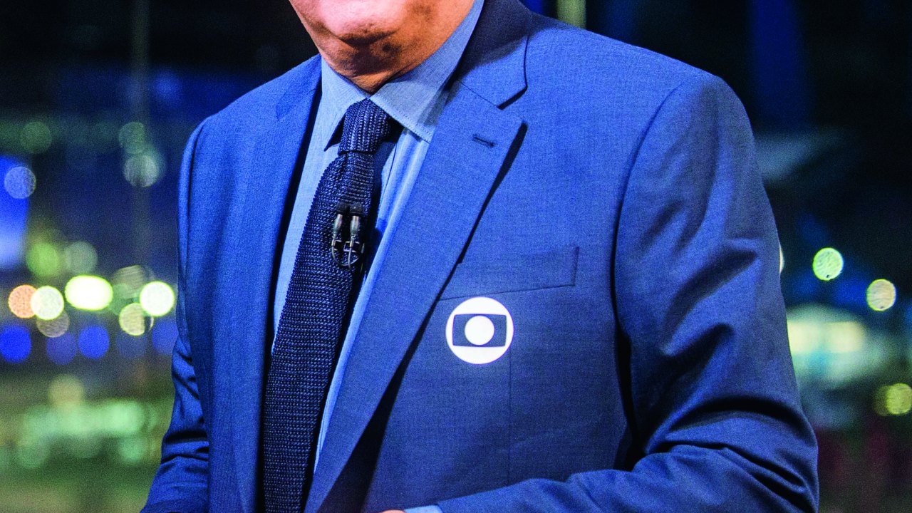 Imagem mostra homem de terno azul, sorrindo.