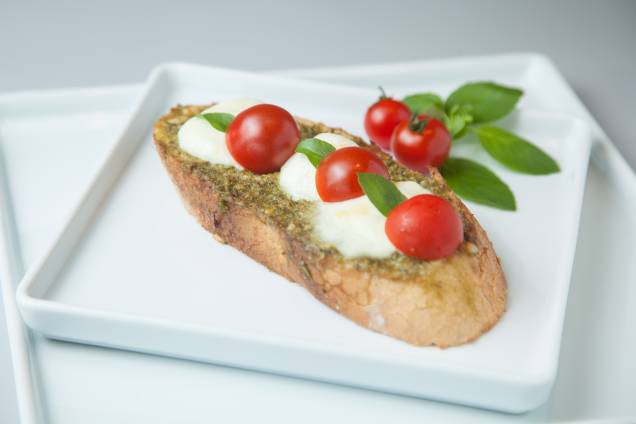 Tostada no filão italiano coberta por alho, molho pesto, tomate-cereja, mussarela de búfala e manjericão Tostada no filão italiano coberta por alho, molho pesto, tomate-cereja, mussarela de búfala e manjericão