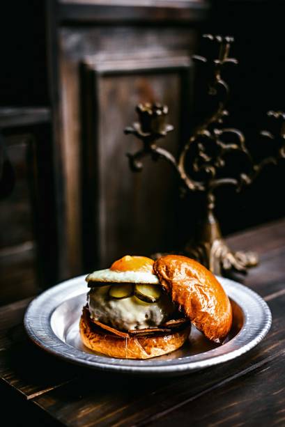 Hambúrguer sertó: queijo meia-cura, pepino em conserva, maionese, bacon e ovo frito de gema mole no brioche