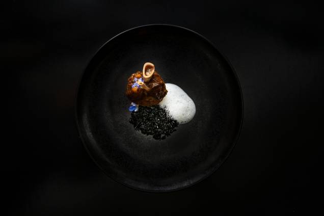Prato de cordeiro: stinco cozido, guarnecido de arroz-negro com lascas da carne e espuma de castanha-do-pará Prato de cordeiro: stinco cozido, guarnecido de arroz-negro com lascas da carne e espuma de castanha-do-pará