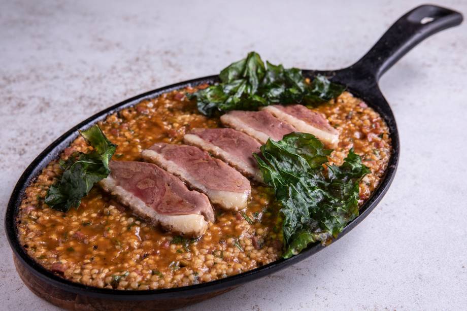 Arroz de pato: servido na panela de ferro com azeitona, couve e fatias do peito da ave Arroz de pato: servido na panela de ferro com azeitona, couve e fatias do peito da ave