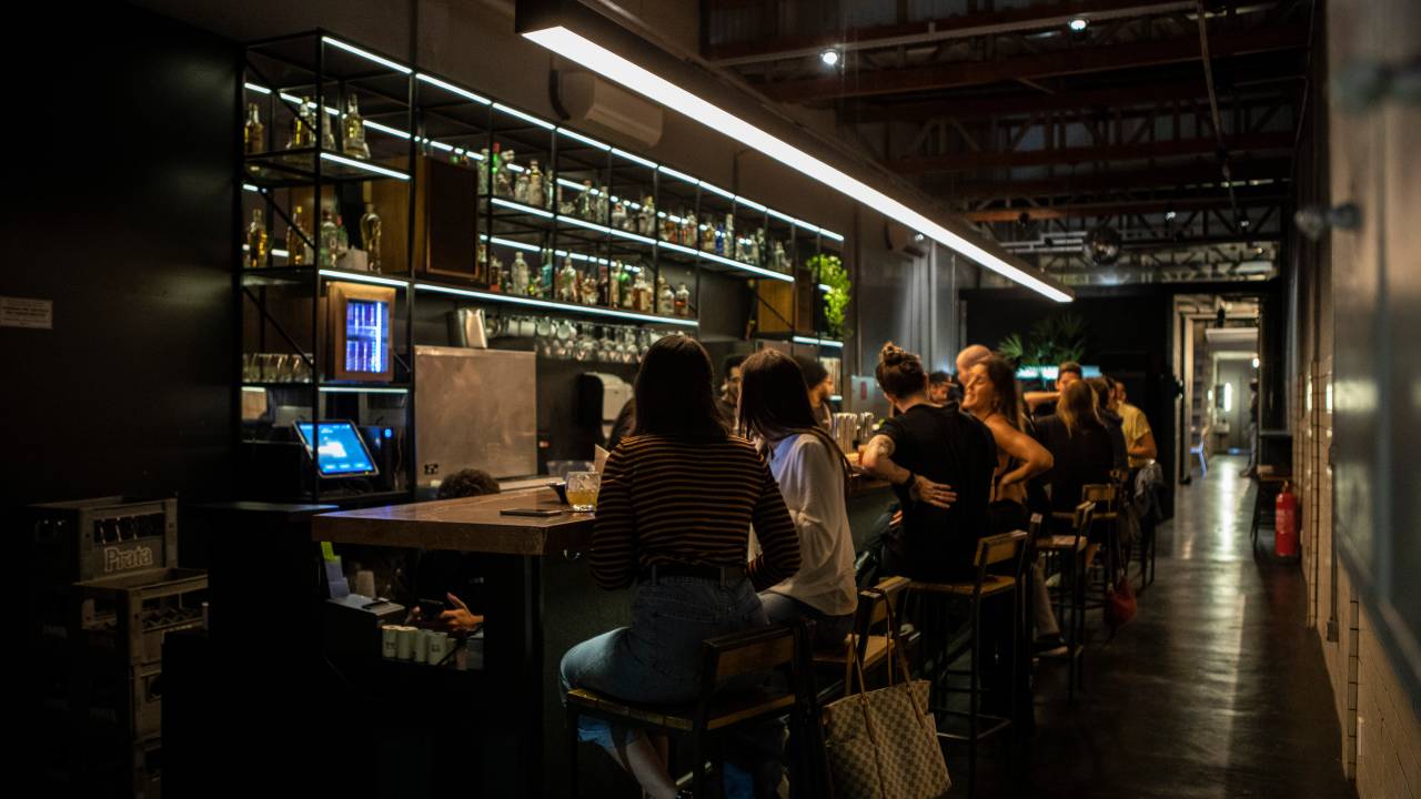 Ambiente escuro com pessoas em banquetas