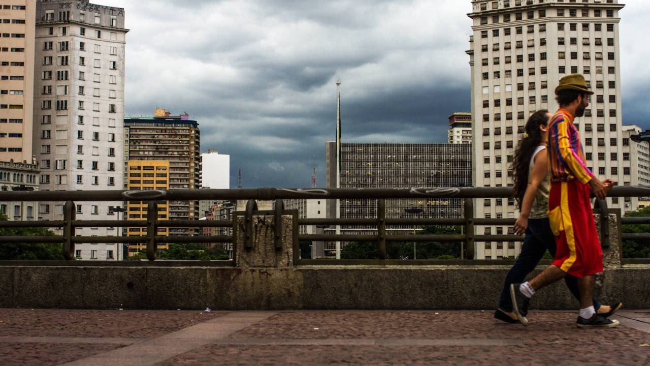 A imagem mostra duas pessoas caminhando em viaduto no centro de São Paulo