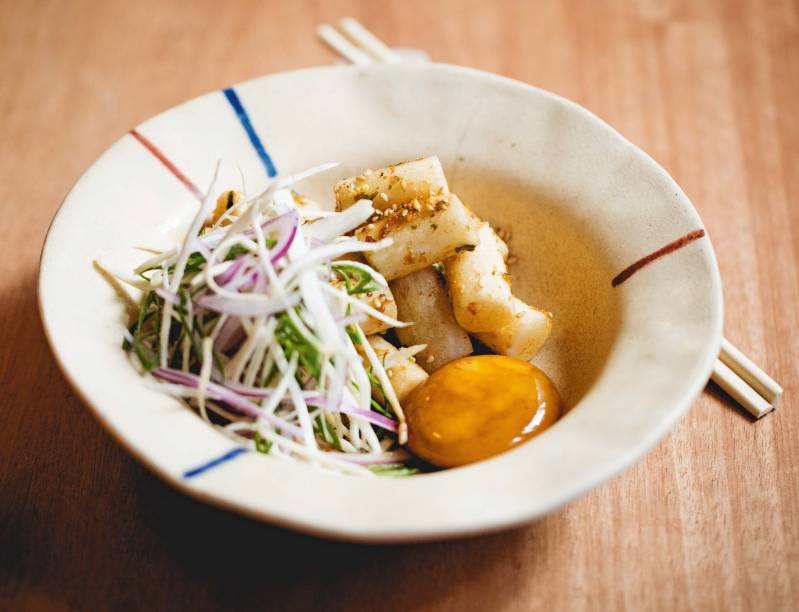 Topoki: cilindros de massa de arroz grelhados e crocantes, servidos com gema de ovo curada, cogumelo, cebola-roxa e molho de saquê mirin Topoki: cilindros de massa de arroz grelhados e crocantes, servidos com gema de ovo curada, cogumelo, cebola-roxa e molho de saquê mirin