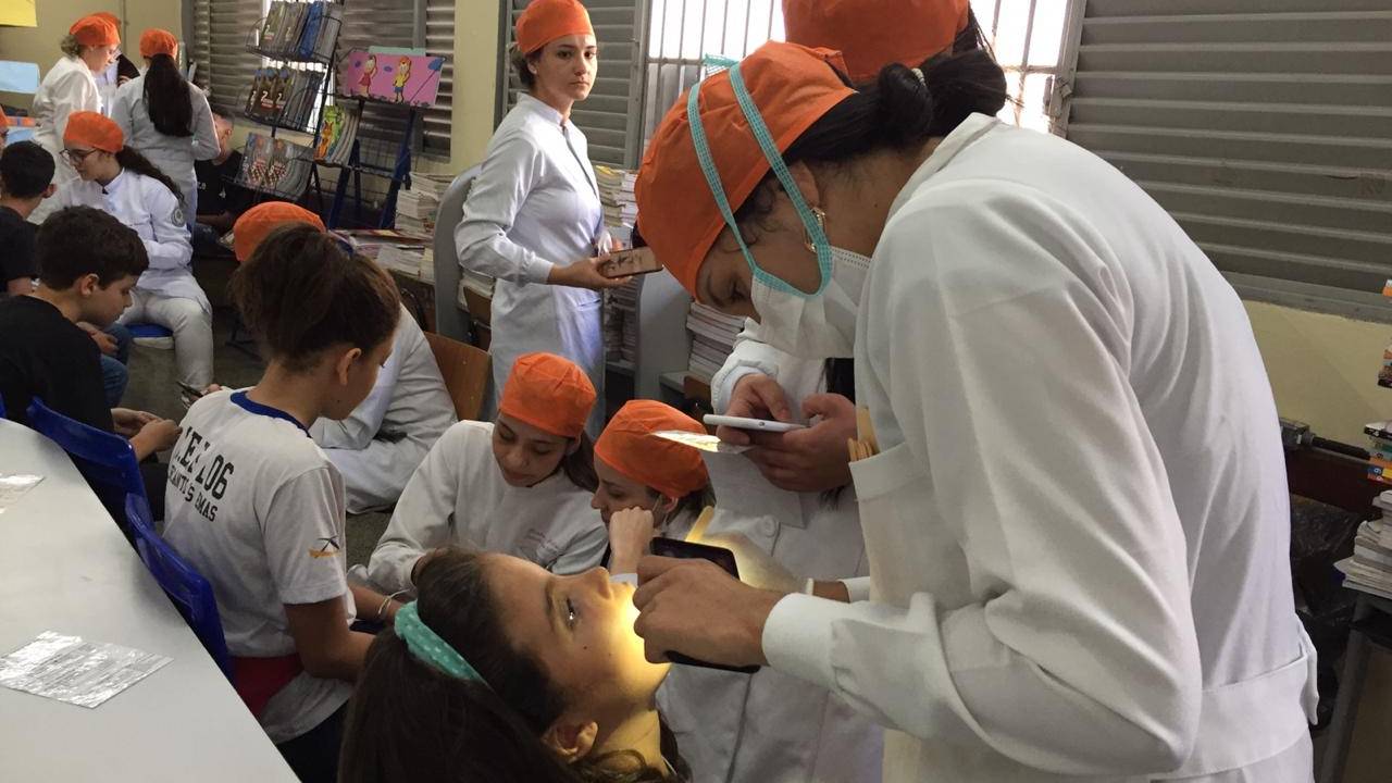 Imagem mostra criança em consultório de dentista, sendo atendida por uma dentista.