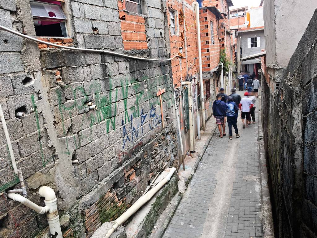 Paraisópolis Beco em Paraisópolis com jovens andando à frente.