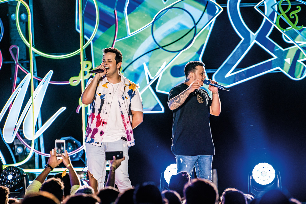 Dois cantores em cima de palco com microfones na mão
