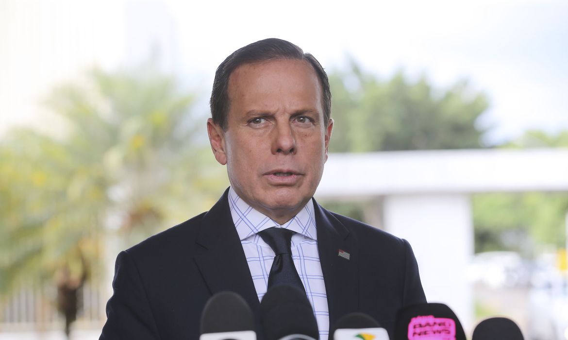 A imagem mostra a cara de João Doria, durante uma coletiva de imprensa. Ele está com o rosto sério.