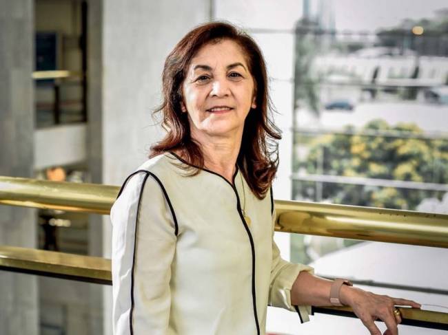 Marta Costa Marta Costa, apoiada em um corrimão dourado, com uma roupa branca e sorrindo para a câmera