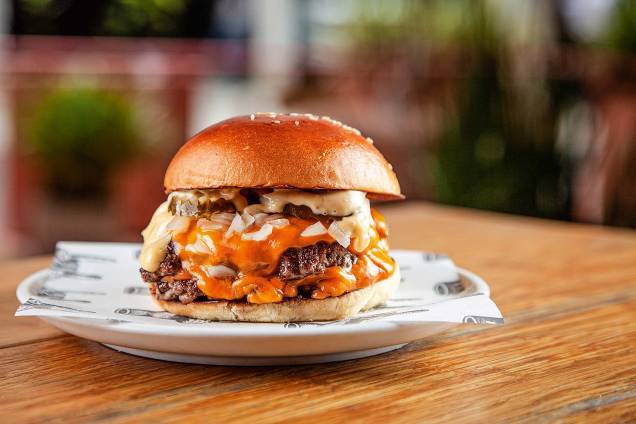 O j.r. burger traz dois discos finos de carne com queijo americano, cebola, picles e molho O j.r. burger traz dois discos finos de carne com queijo americano, cebola, picles e molho