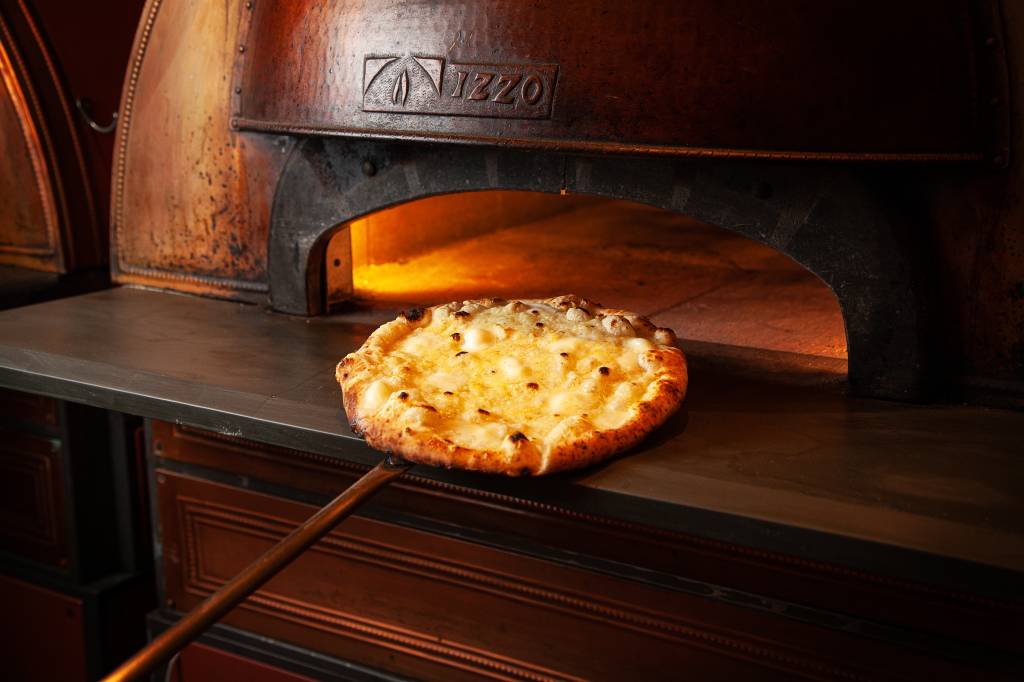 Bráz Elettrica serve deliciosa pizza de queijos com alho em espaço hipster