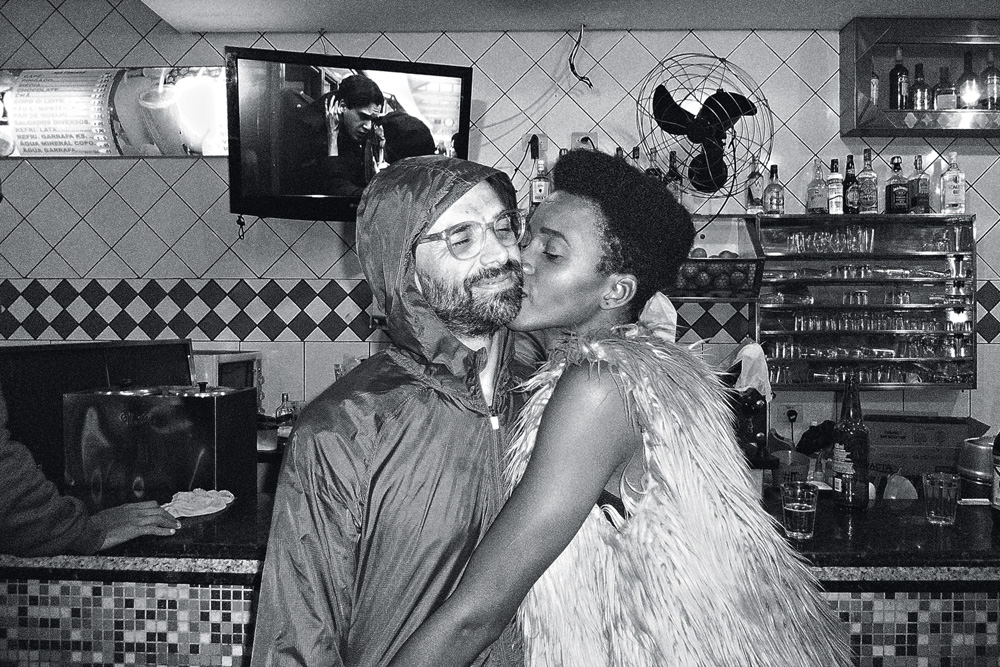 Bárbara Britto e Leo Felipe Foto em preto e branco de Bárbara dando um beijo no rosto de Leo