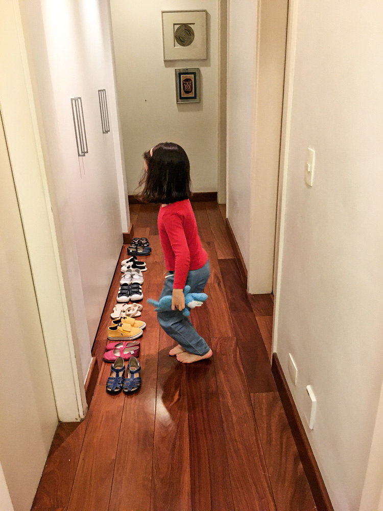 circuito dos sapatos Um corredor com uma criança em frente a uma fila de sapatos