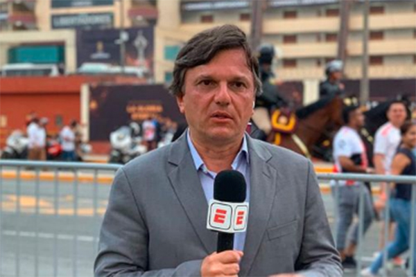 Foto mostra o jornalista Mauro Cezar de terno com microfone que exibe o logo da ESPN