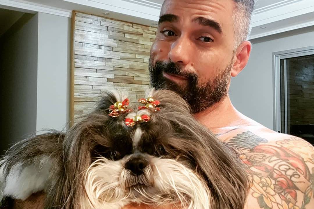 Advogado Marcelo Silva segura sem camisa sua shih-tzu de estimação.